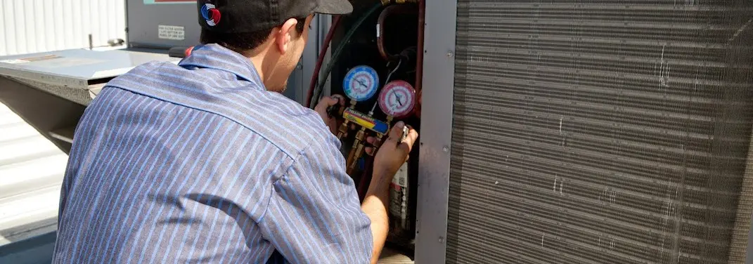 HVAC technician servicing a condenser unit in Manassas Park